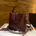 Vintage dark brown leather bucket bag with top handle and crossbody strap, detailed view. - Wine Coffee