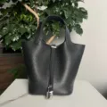 Primo piano dettagliato di borsa a secchiello nera in pelle con lucchetto e manici argentati. - Cinturino Nero Fibbia Argento