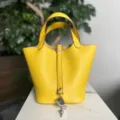 Vista dettagliata della borsa a secchiello in pelle gialla con grana fine e lucchetto. - Giallo di Napoli con fibbia argentata