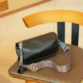 Black leather barrel shoulder bag with colorful wide strap and metal hardware detail. - Black