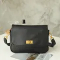 Detailed view of black leather vintage crossbody shoulder bag with golden metal hardware lock. - Black