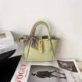 Green leather bucket bag detail featuring luxury metal turn-lock and stylish scarf accent. - Avocado Green [In Stock]