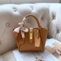 Brown leather bucket bag with top handle, elegant gold lock and stylish scarf accessory. - Biscuit [In Stock]