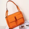 Orange Togo leather shoulder bag with dual front pockets, stylish crossbody tote for women. - Orange
