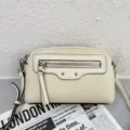 Elegant beige leather crossbody bag with front zipper and distinctive metal stud details. - Off White