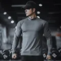Detailed shot of mens solid color long sleeve fitness t shirt in gym setting, premium fabric. - High Neck Dark Gray