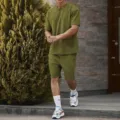 Olive green mens casual sportswear detail, short sleeve t-shirt and shorts set background scene. - Army Green