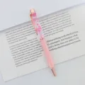 Detalle de un bolígrafo rosa con flores secas flotando en aceite sobre un libro abierto. - Punta de Bala de 1,0 mm / Rosa