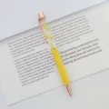 Detailed view of a yellow ballpoint pen with dried flowers floating in oil on a book - 1.0mm Bullet Tip / Yellow