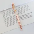 Elegant rose gold ballpoint pen with yellow dried flowers displayed on an open book. - 1.0mm Bullet Tip / Rose Gold (Yellow Flower)