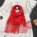 Detail view of red sheer organza scarf featuring sparkling glitter stripes and elegant pearl accents. - Deep Red