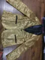 Detail view of men's luxury gold sequin blazer featuring classic black lapel and pocket trim. - Gold