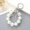 Elegante portachiavi da polso con perle bianche e ciondolo a fiocco in metallo per borsa - Ciondolo Fiocco a Nastro & Perle Artificiali (K4709)
