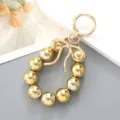Ciondolo per borsa con perle metalliche dorate, fiocco e moschettone rotondo - Ciondolo Fiocco a Nastro & Perline Oro (K4712)