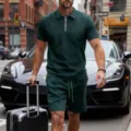 Street style detail of dark green geometric patterned zip polo shirt and shorts set with suitcase. - Dark Green