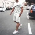 Detailed view of men's casual white short sleeve t-shirt and shorts set showcased in street scene. - S / Tops / White