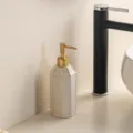 Vue détaillée d'un distributeur de savon en céramique avec pompe dorée et design épuré. - Flacon de savon liquide [or - tête ronde]