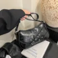 Black leather motorcycle shoulder bag with metal buckles and stylish rivet details for women. - Black