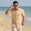 Detailed view of men's casual short sleeve beach linen shirt worn on sandy beach outdoors. - Khaki