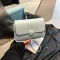 Elegante bolso de hombro azul claro con refinada textura tejida y cierre de solapa. - Azul