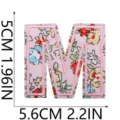 Primo piano della toppa ricamata con lettera M a fiori rosa e dettagli di cucitura. - C13SH-07-M