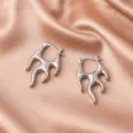Detailed view of silver flame-shaped punk hoop earrings on soft champagne satin fabric - Flame-Shaped Hoop Earrings (E177) / Standard / Platinum Color (E177)