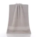 Serviette de visage en coton uni avec bordure satin double, douce et absorbante gris. - Gris clair