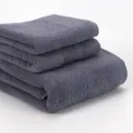 Détail de serviette en coton gris empilée, vue rapprochée texture douce avec motif tissé. - Bleuet