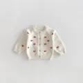Detailed view of the baby girl knit cardigan in cream white with cute red heart embroidery. - 73cm / Off White