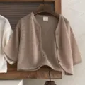 Detailed view of the kids minimalist knit cardigan, featuring breathable fabric and wooden buttons. - 66cm / Brown