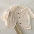 Detail shot of cream baby cardigan, lightweight sheer knit texture, wooden buttons, infant top. - 73cm / Beige