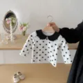 Detailed view of baby polka dot long sleeve top with black collar on wooden shelf display. - 66cm / Black White Polka Dot