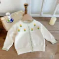 Charming baby knit cardigan detail featuring delicate yellow floral embroidery and green trim. - 66cm / White & Apricot Cardigan