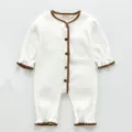 Detailansicht des weißen Baby-Stramplers mit brauner Häkelborte und Holzknöpfen. - 80cm / Weiß