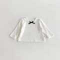 Détails rapprochés du t-shirt à manches longues côtelé blanc pour bébé avec joli nœud. - 66cm / Blanc