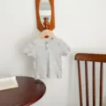 Λεπτομέρεια βρεφικού γκρι ριμπ t-shirt κοντό μανίκι με πατιλέτα κουμπιών σε ξύλινη κρεμάστρα. - Γκρι / 66cm