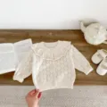 Close-up detail of cream baby knit cardigan with hollow-out pattern and big ruffle collar. - 66cm / Beige Apricot