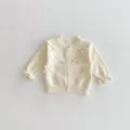 Detalle del cárdigan de punto para bebés con bonitos lazos y elegantes mangas con volantes. - 66cm / Albaricoque