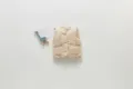 Detailed view of beige quilted baby vest with snap buttons and front pockets for winter. - 66cm / Apricot