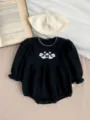 Detailed closeup of black baby romper with white floral embroidery and cute scalloped collar. - 66 / Black