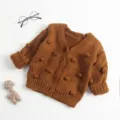Gedetailleerd overzicht van bruin gebreid babyvest met handgemaakte pompons voor de herfst. - 90cm / Bruin