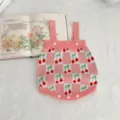 Detailed shot of a cute pink checkered baby knitted romper featuring lovely cherry patterns and buttons. - 66cm / Baby Romper