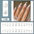 Detailed view of almond press on nails with cute black heart design, glossy finish and elegant. - Milky White Black Heart Long Almond (Y-08) / Glue Type