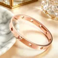 Gedetailleerd close-up van een modieuze roségouden roestvrijstalen sterrenarmband. - Rozegouden Stijl (MSXBG00000773R)