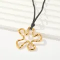 Primer plano de collar con colgante de flor irregular dorada y cordón negro, detalle elegante. - Estilo de Diseño de Pétalo Irregular