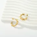 Pendientes de aro con tachuelas de acero dorado, detalle de remaches punk de cerca. - Estilo Punk Remaches