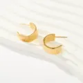 Detalle de pendientes de aro minimalistas en acero de titanio chapado en oro de 18k. - Estilo Texturizado de Ranuras Verticales