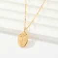 Disparo detallado de collar dorado con un elegante colgante ovalado de rosa grabada. - Rosas irregulares