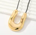 Primer plano detallado de un collar con dije dorado en forma de U, diseño moderno minimalista. - Estilo de Línea Asimétrica Geométrica en U