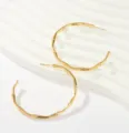 Detail view of stylish gold-toned hoop earrings featuring an elegant bamboo texture. - Large Bamboo Joint Hoop Earrings (Style 3)